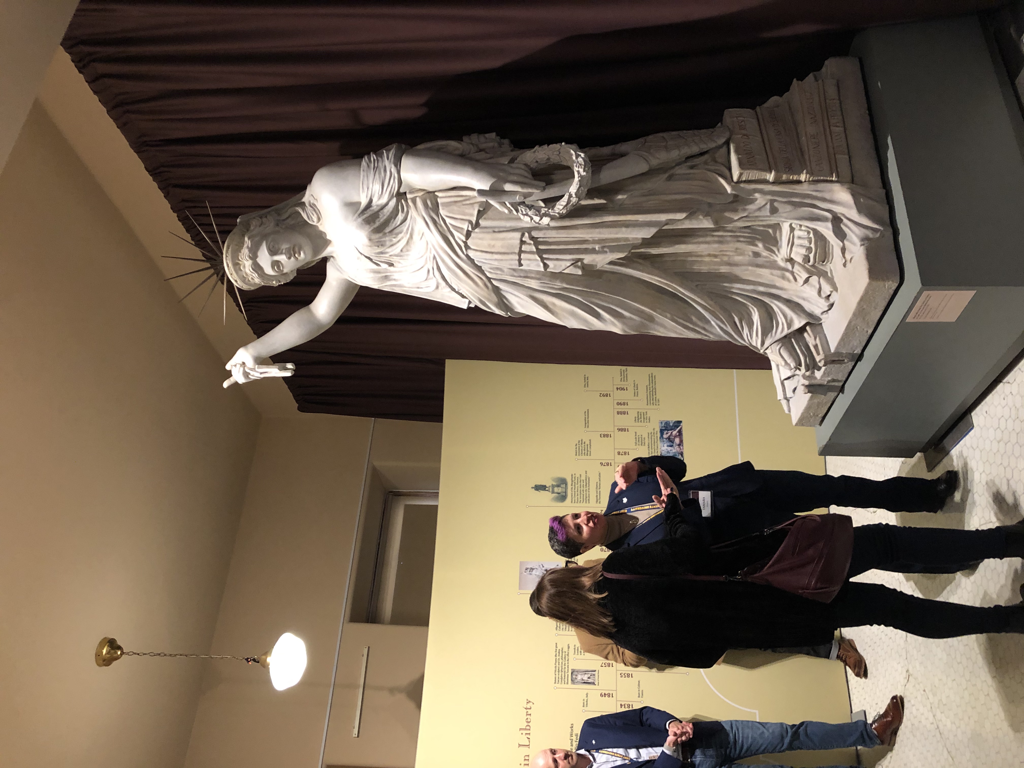 Visitors in the gallery viewing the statue